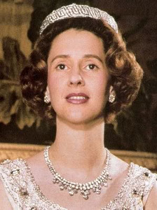 Koningin Fabiola die zittend in witte avondjurk poseert en de tiara draagt als collier